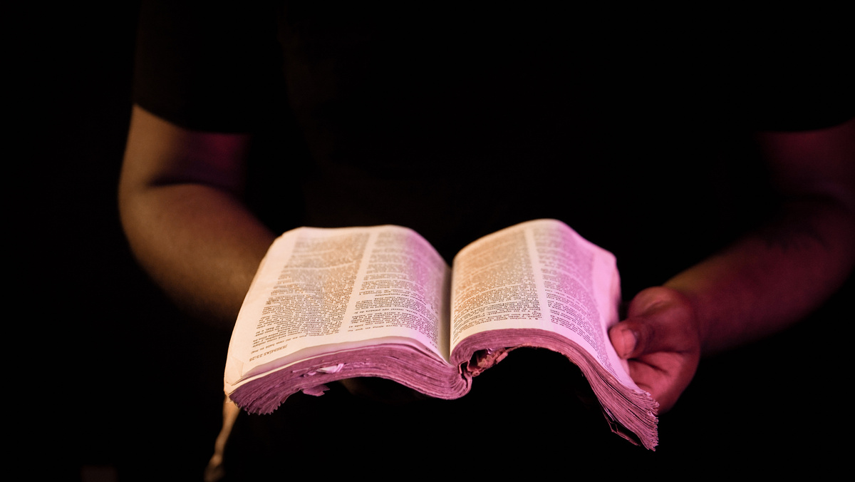 Person Holding Bible With Black Background