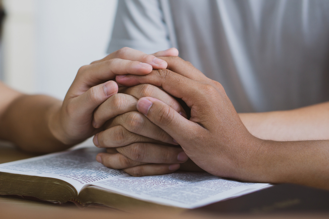 ing Prayer meeting concept.Colleagues shaking hands reading scriptures and praying to God at work place.Prayer, trust, hope, gratitude concept