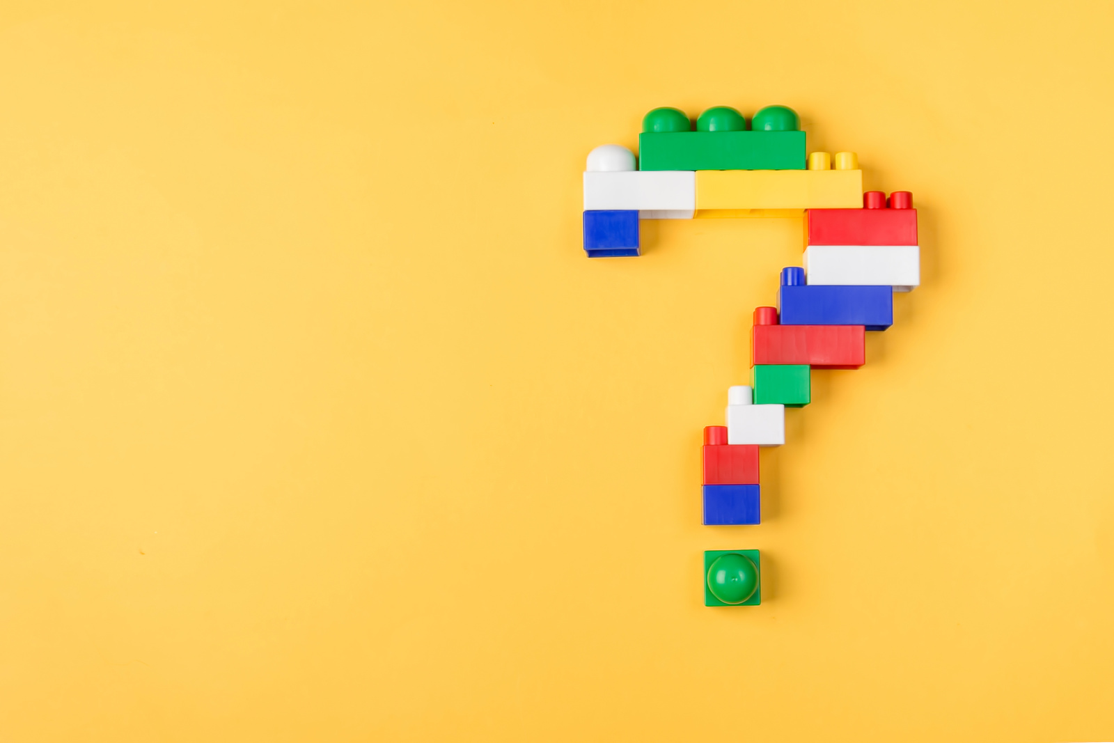 Details of a children's toy constructor folded as a question mark on a yellow background. Creative and educational concept.